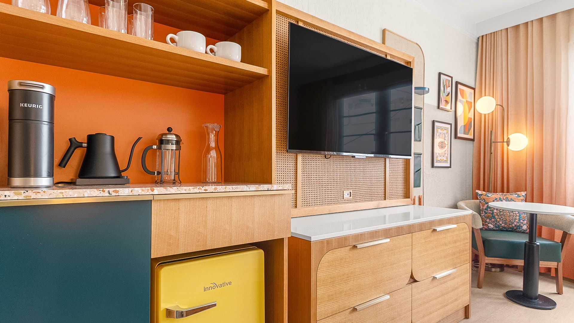 a kitchenette with a coffee set, a television and a yellow fridge