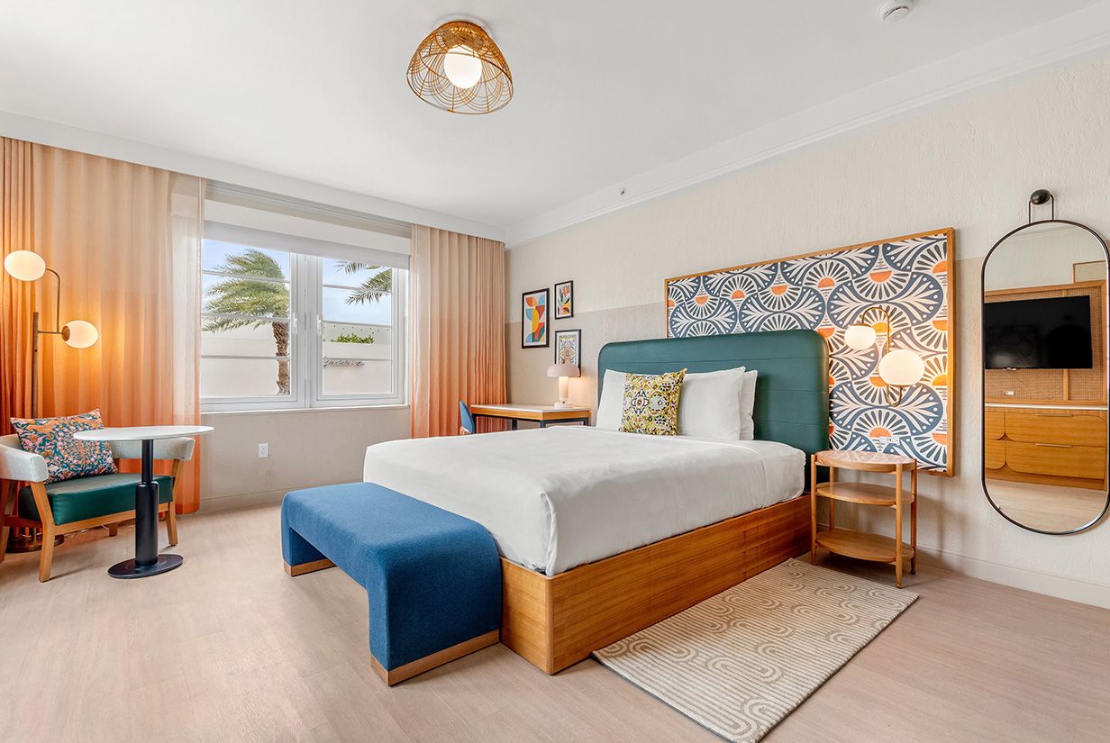 a bright room with a king bed and a patterned headboard