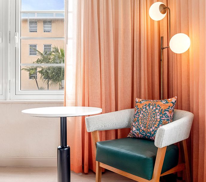 un sillón verde azulado y una mesa redonda junto a la ventana