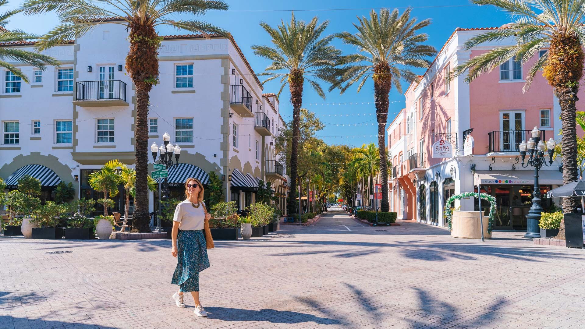 a guest walking past pastel buildings and palm trees