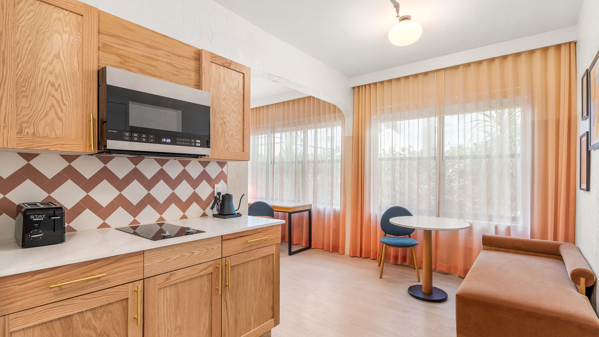 a suite kitchen with wooden cabinets and a patterned backsplash