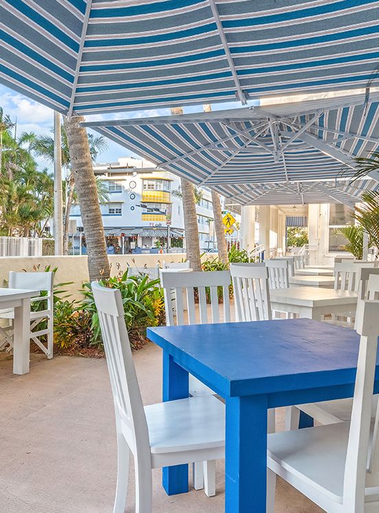 una mesa azul en la terraza con toldo a rayas